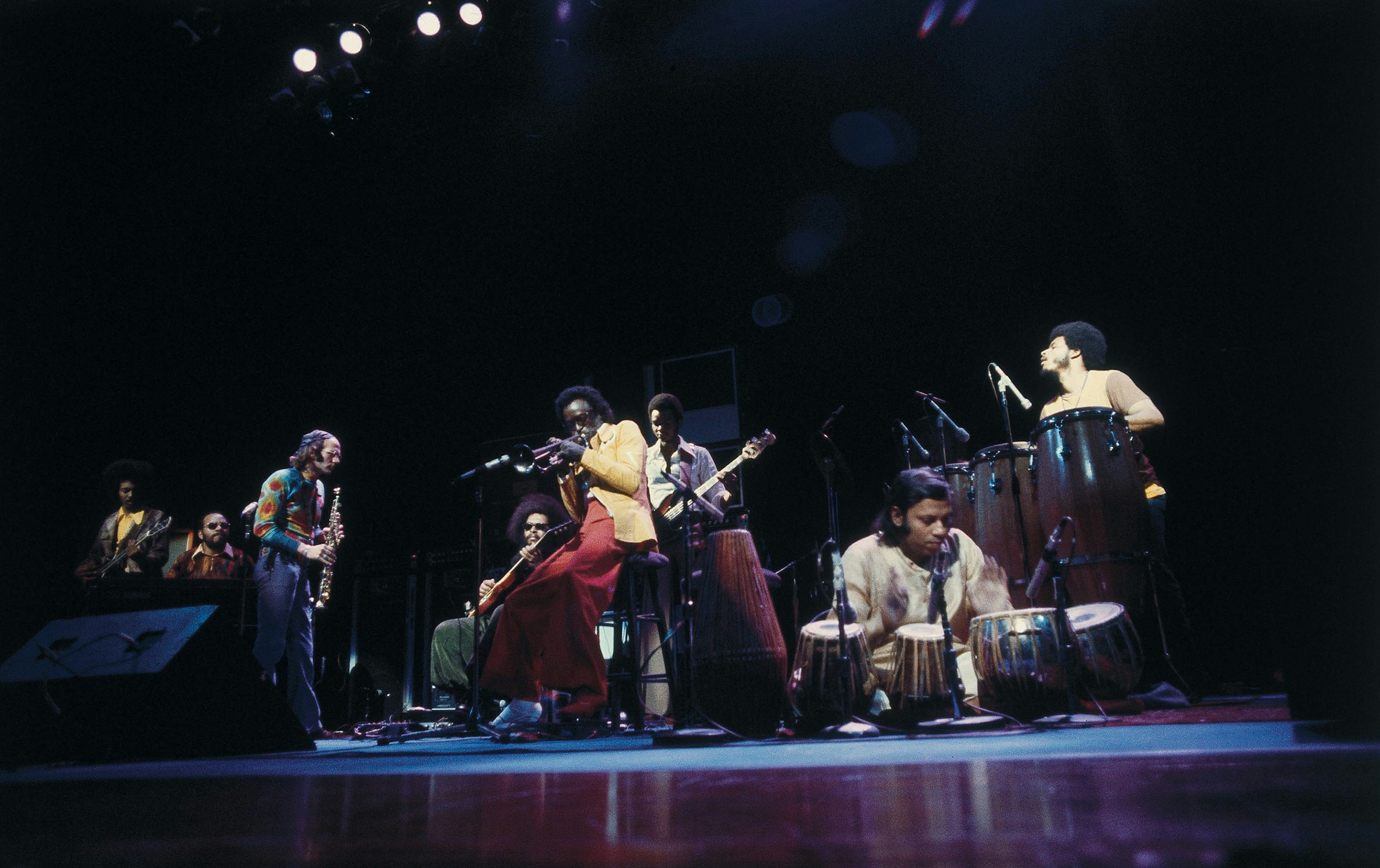 Reggie Lucas on guitar, Lonnie Liston Smith on organ, Dave Liebman on soprano sax, Pete Cosey on guitar (sitting), Miles Davis, Michael Henderson on bass, Badal Roy on tablas, and Mtume on percussion. Photo by Urve Kuusik. Courtesy of Sony BMG Music Entertainment.